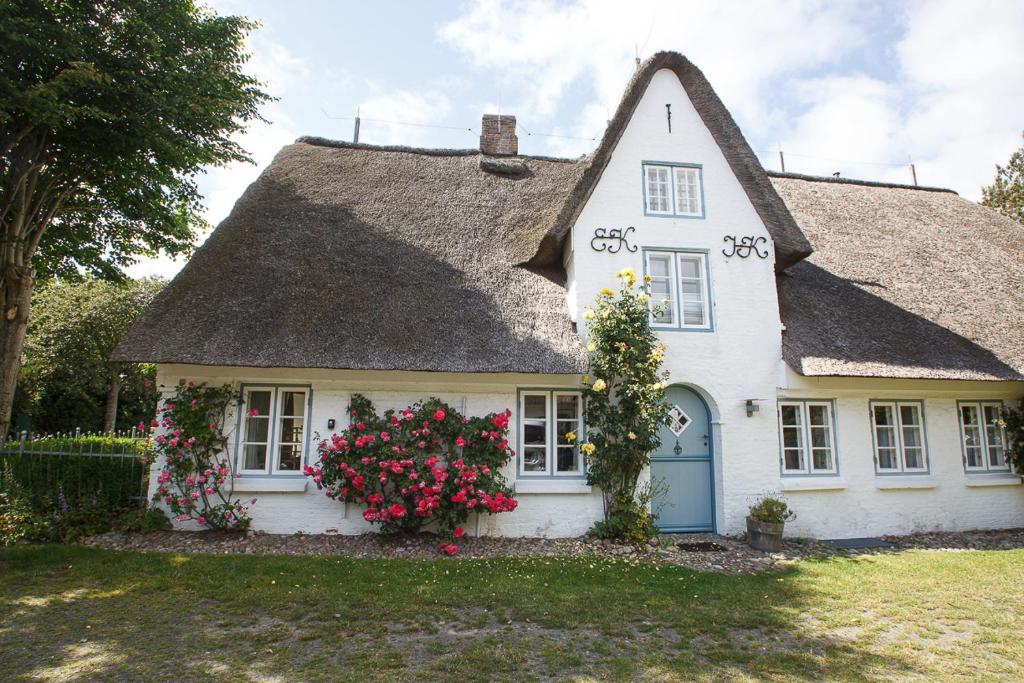 a white house with a thatched roof with flowers at Oevenum Vogelkoje in Oevenum EG in Oevenum