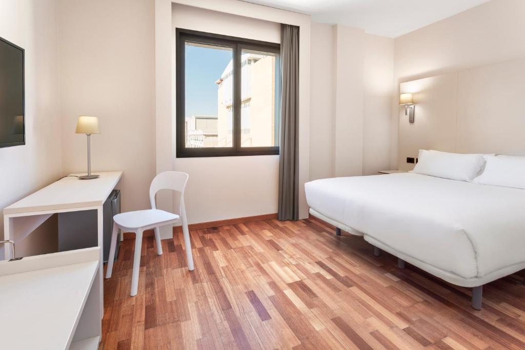 Un dormitorio con una cama y un escritorio y una ventana. en B&B HOTEL Elche, en Elche