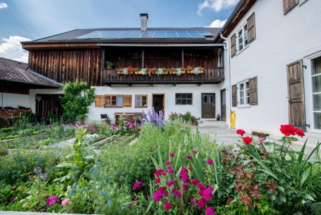 un jardin avec des fleurs en face d'une maison dans l'établissement Ferienwohnung Lacherhof, à Seehausen am Staffelsee