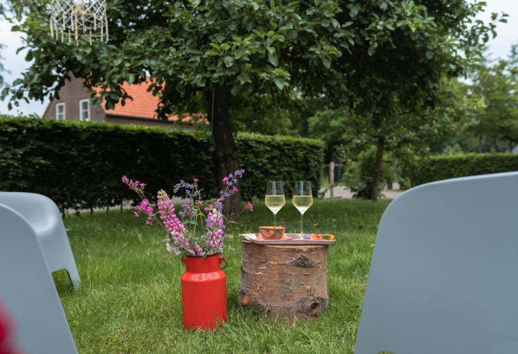 two glasses of white wine and a table with flowers at B&B De Ouw Skuur in Oirschot