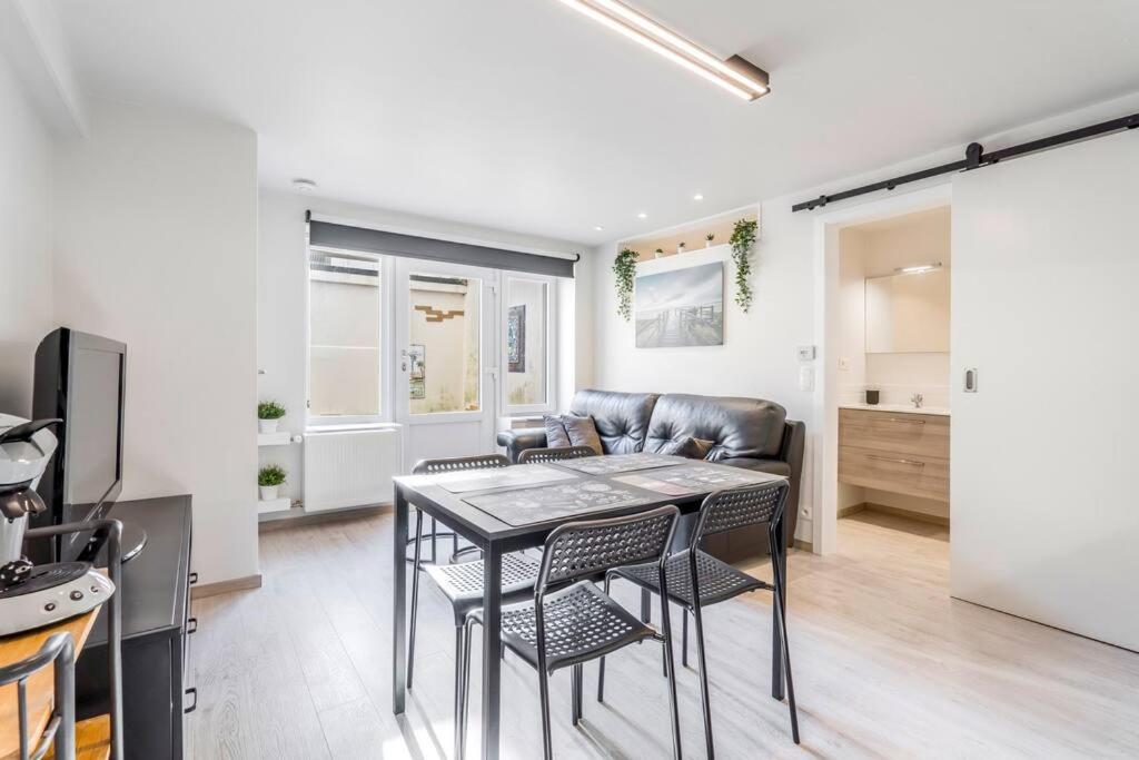 a living room with a table and chairs and a couch at Comfortabele, moderne studio zeedijk De Panne in De Panne