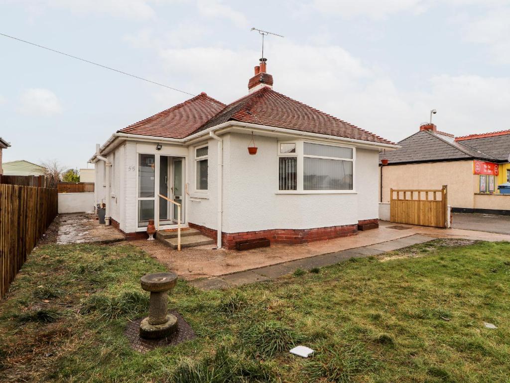 a white house with a fence in a yard at 55 Marine Road in Abergele