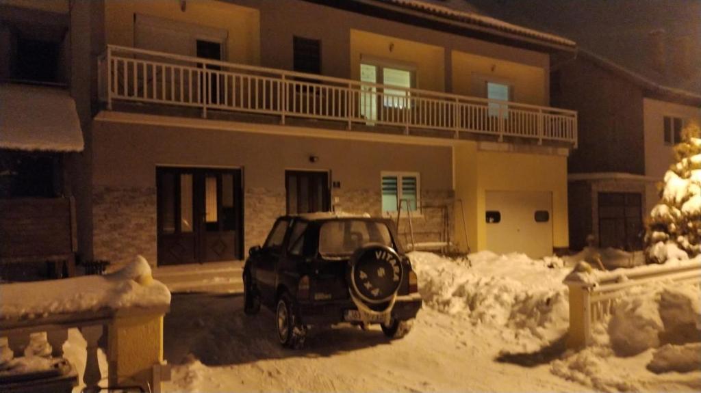 ein Auto, das im Schnee vor einem Haus parkt in der Unterkunft Apartman Ivano in Kupres