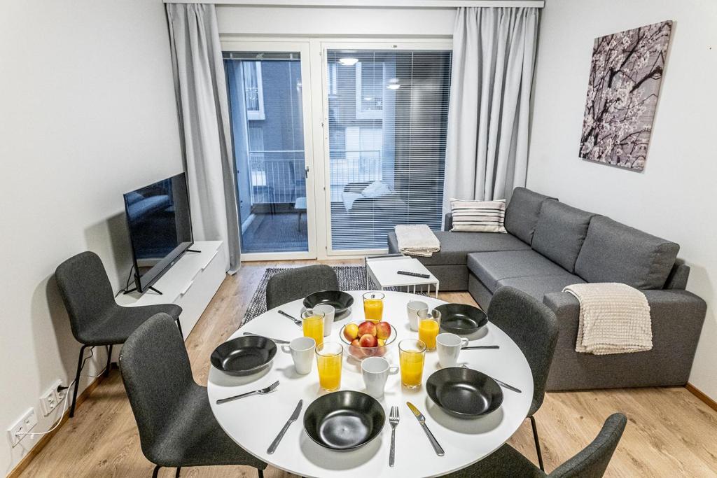 a living room with a table and a couch at SleepWell Apartment Rio with private sauna and parking in Helsinki