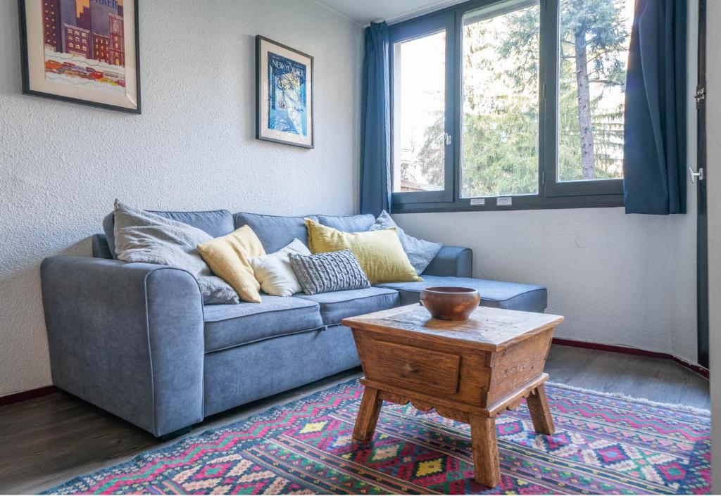 ein Wohnzimmer mit einem blauen Sofa und einem Tisch in der Unterkunft Chamois Blanc Terrasse in Chamonix-Mont-Blanc