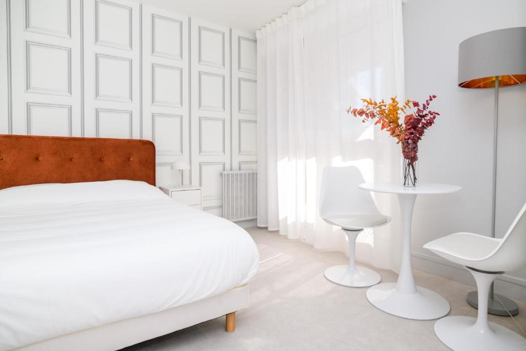 a white bedroom with a bed and a table and chairs at The Luxe Lake - Duke Housing in Créteil