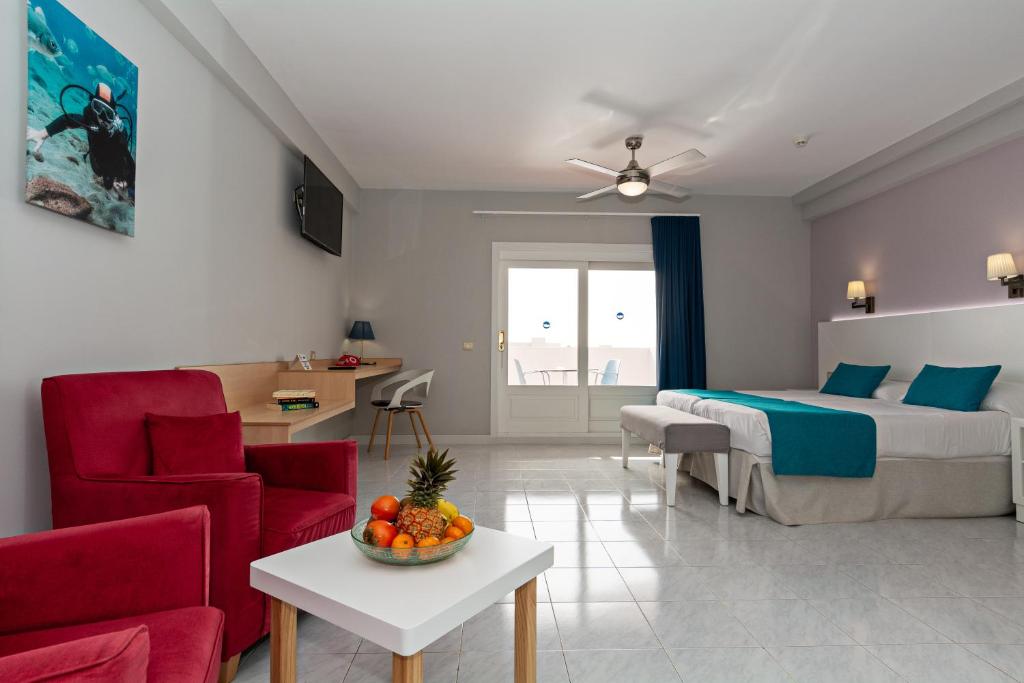 a bedroom with a bed and a table with a bowl of fruit at Apartamentos Oceano - Adults Only - Sólo Adultos in Costa Teguise