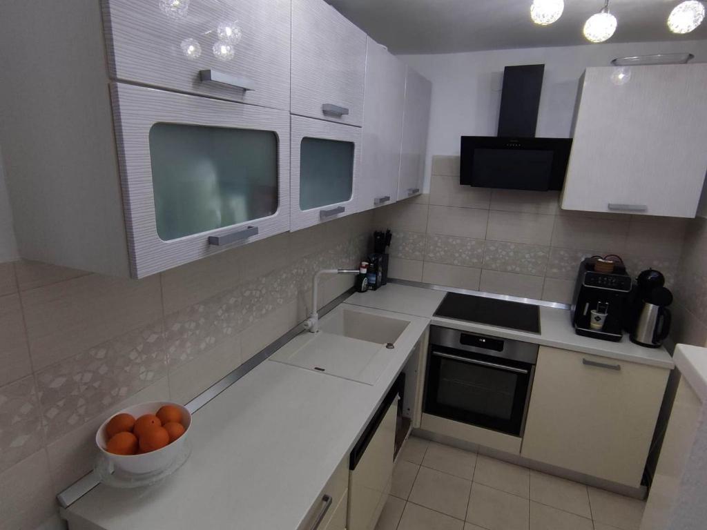 a kitchen with white cabinets and a bowl of oranges on the counter at Apartment Roki in Zagreb