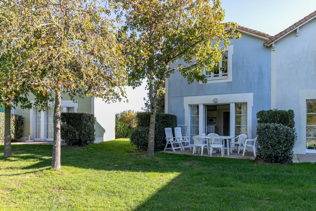 a house with a table and chairs in the yard at Maison pour 6 - Piscine - Port Bourgenay in Talmont-Saint-Hilaire