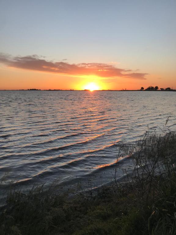 una puesta de sol sobre un cuerpo de agua con una playa en Excelente Ubicación con Patio y Parrilla Departamento Luminoso y con Desayuno en Junín