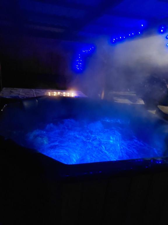 wanna z hydromasażem z błękitną wodą w nocy z oświetleniem w obiekcie Szikla Vendégház w mieście Istenmezeje