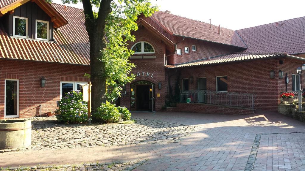 a brick building with a tree in front of it at Hotel Restaurant Am Pfauenhof in Quakenbrück