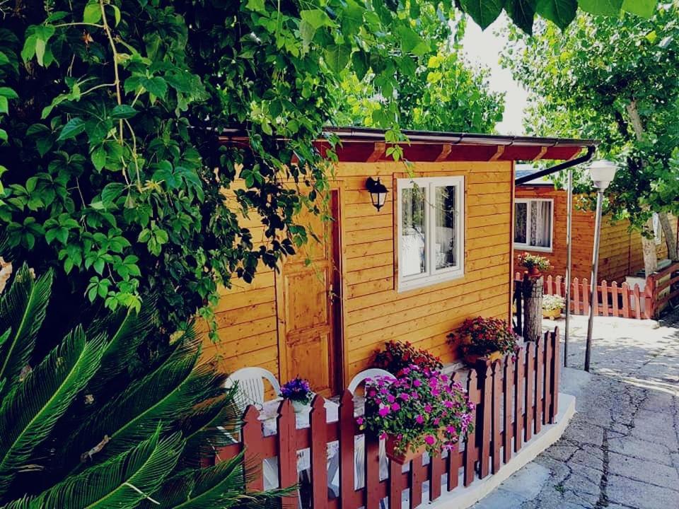 una pequeña casa amarilla con una valla y flores en Camping Onda Azzurra en Ortona