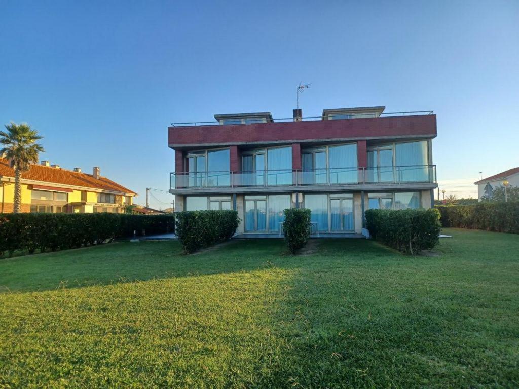 a large house on a grassy yard with bushes at Apartamentos Playa de Portio in Liencres