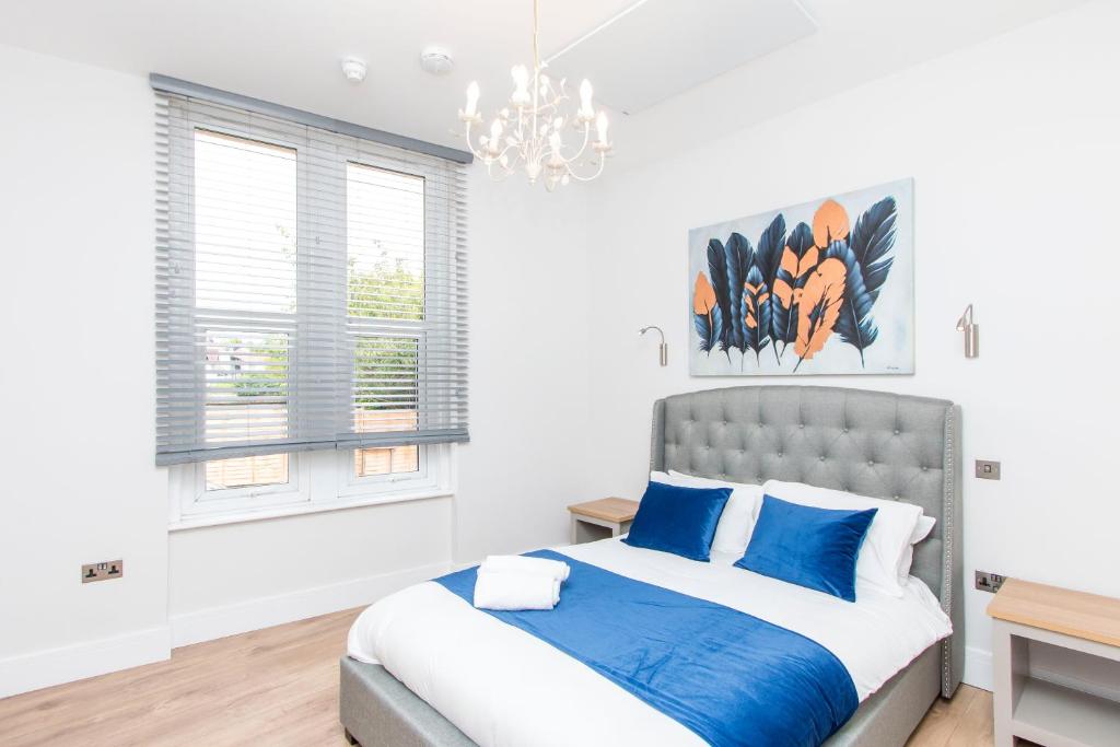 a bedroom with a bed with blue pillows and a chandelier at Coldharbour Suites in Bristol