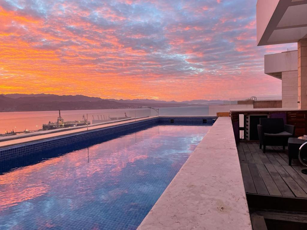 a pool on the roof of a building with a sunset at Private pool Luxury penthouses sea view Eilat in Eilat