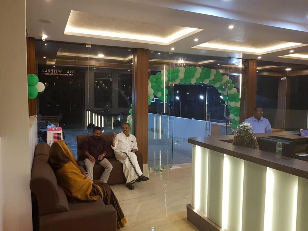 a group of men sitting in a lobby with a bar at Hotel ParkwayInn in Kelambākkam