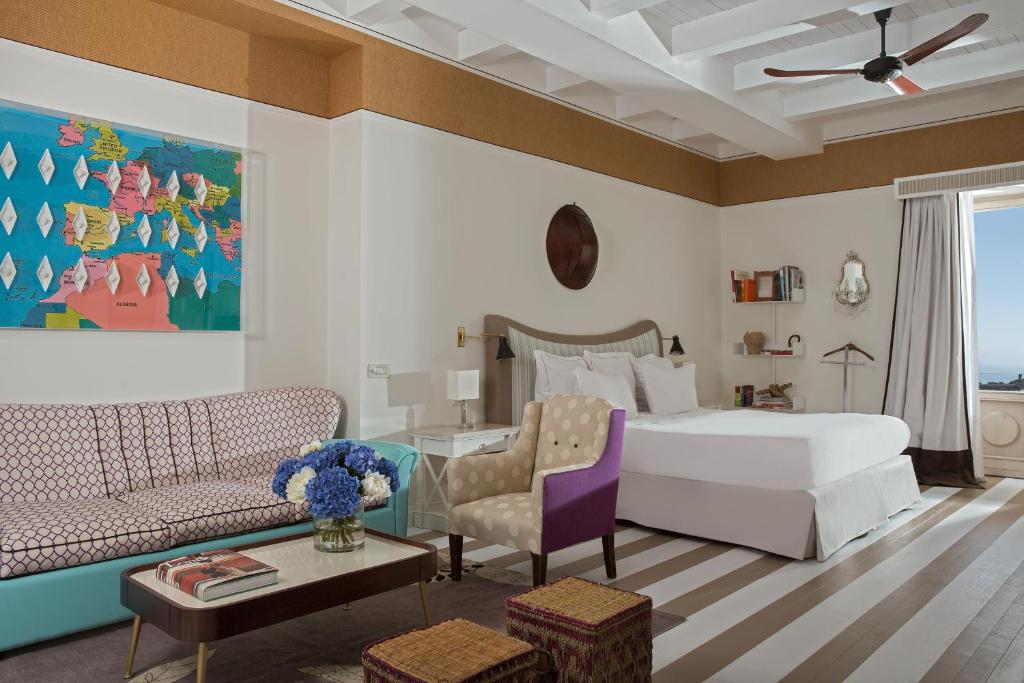 a bedroom with a white bed and a couch at Capri Tiberio Palace - The Leading Hotels of the World in Capri