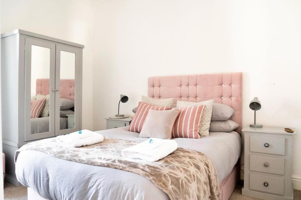 a bedroom with a pink bed with two towels on it at Penarth/Cardiff Bay: Deluxe Flat: 10 Mins to City! in Cardiff