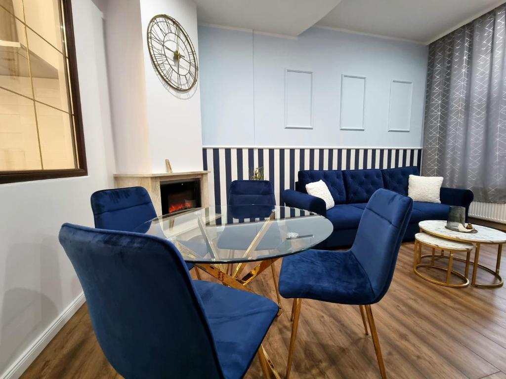 sala de estar con sillas azules y mesa de cristal en Apartament Skandia Blue, en Toruń