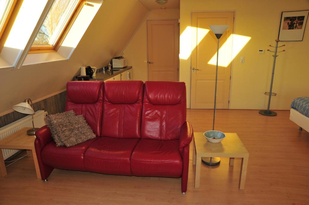 ein Wohnzimmer mit einem roten Sofa und einem Tisch in der Unterkunft Witte Weelde Texel in De Koog