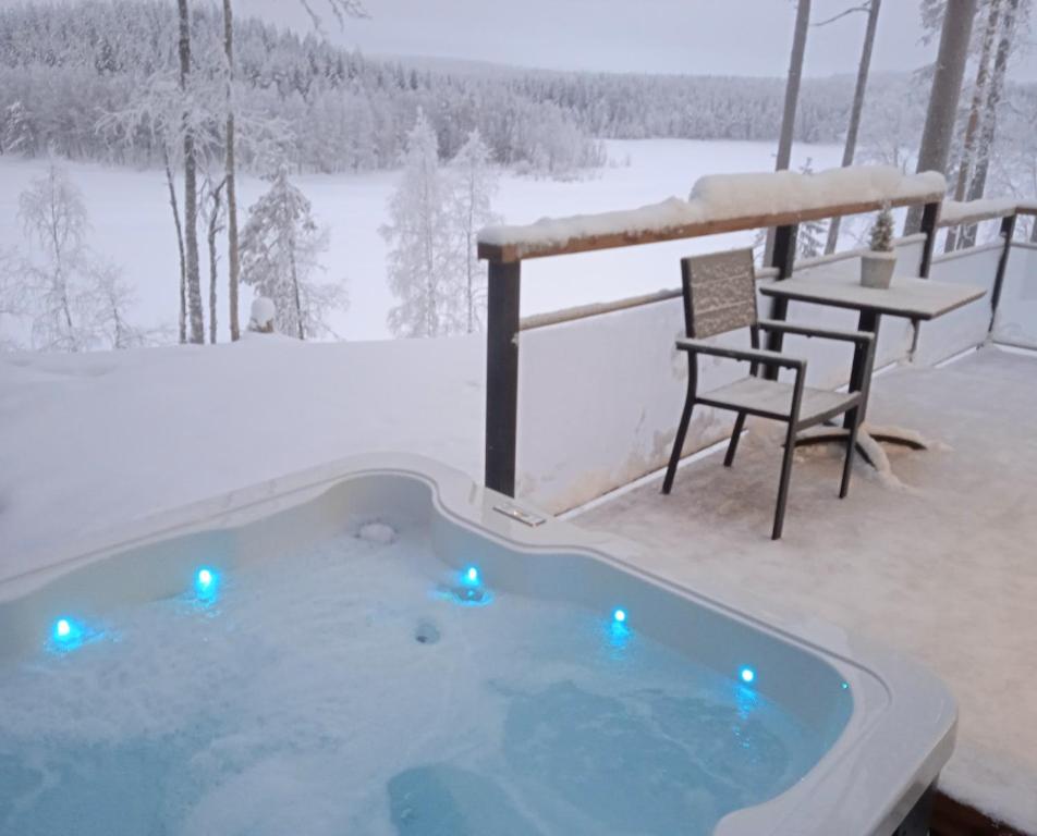 a hot tub in the snow with a table and a chair at Lake Resort Paljakka in Kotila