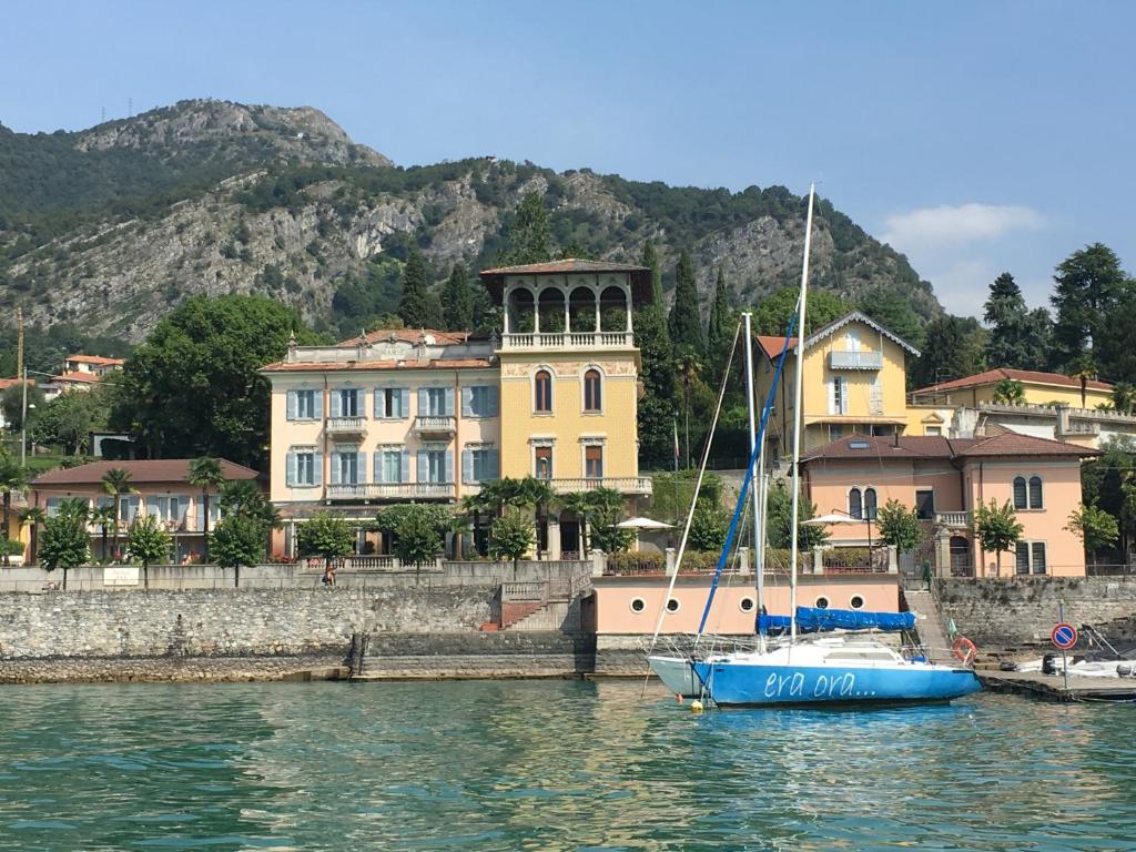 ein blaues Boot im Wasser vor einem Gebäude in der Unterkunft Hotel Villa Marie in Tremezzo