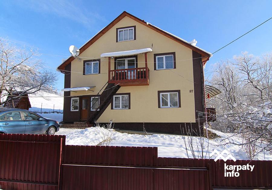 een huis in de sneeuw met een hek en een auto bij Садиба "Барвінок" in Podobovets