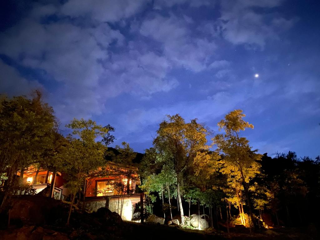 a house at night with the moon in the sky at Pousada Boutique das Pedras in Moeda