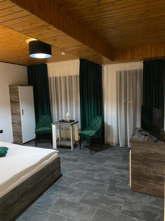 a hotel room with a bed and a table and chairs at Pensiunea Valea Gepisului in Groşi