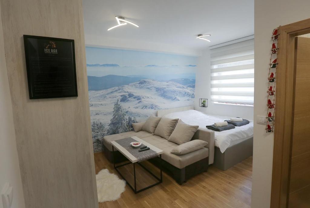 a room with a bed and a couch with a mountain mural at Apartman Ice age Jahorina in Jahorina