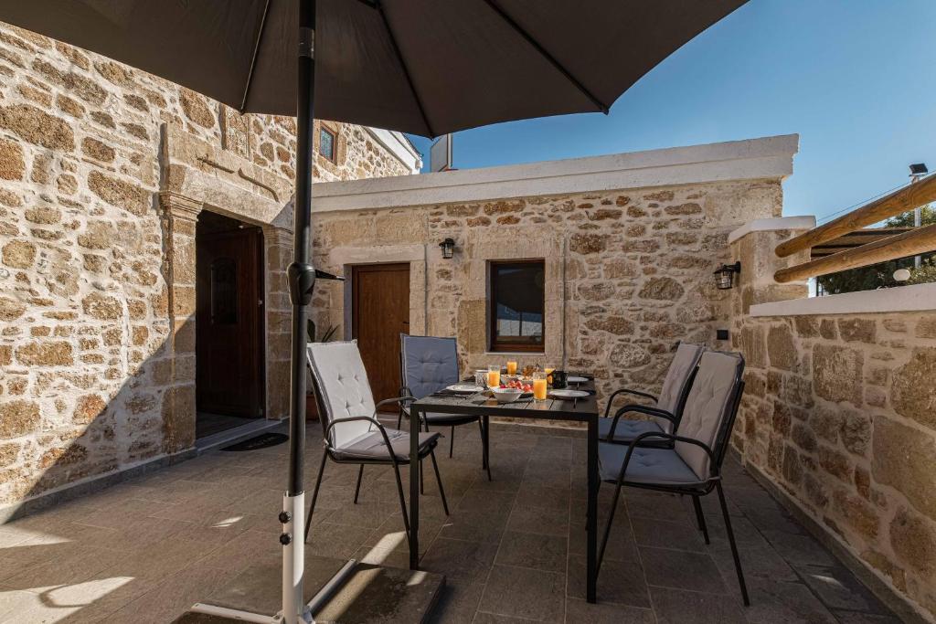 patio ze stołem, krzesłami i parasolem w obiekcie La casa dell'arch w mieście Charaki