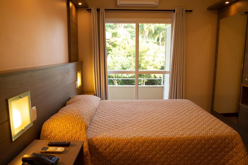 a bedroom with a bed and a window at Dona Adelia Hotel e Restaurante in Flores da Cunha