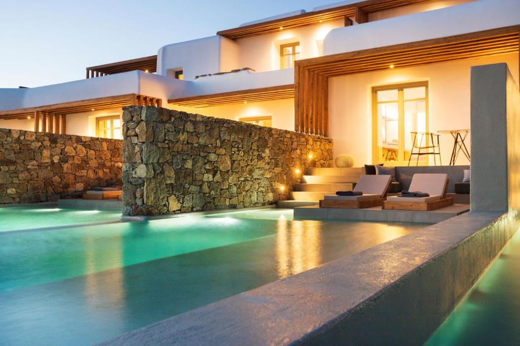 uma villa com piscina em frente a uma casa em Mykonos Soul Luxury Suites em Agios Stefanos