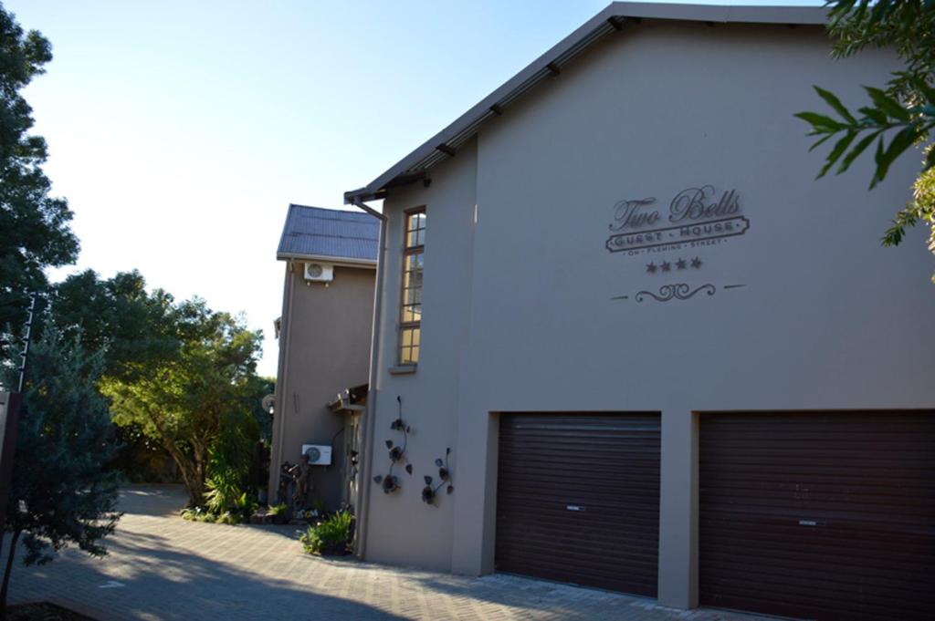 un edificio blanco con dos puertas de garaje. en Two Bells Guest House, en Bloemfontein