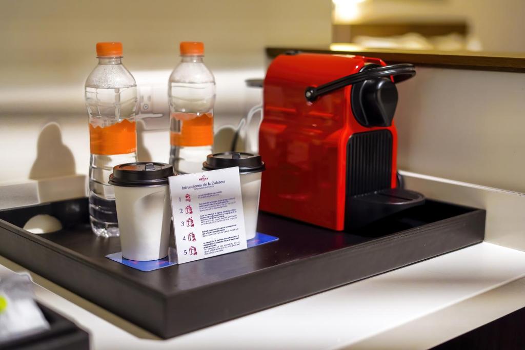 a tray with bottles and a coffee maker on a counter at Metria Hotel in León