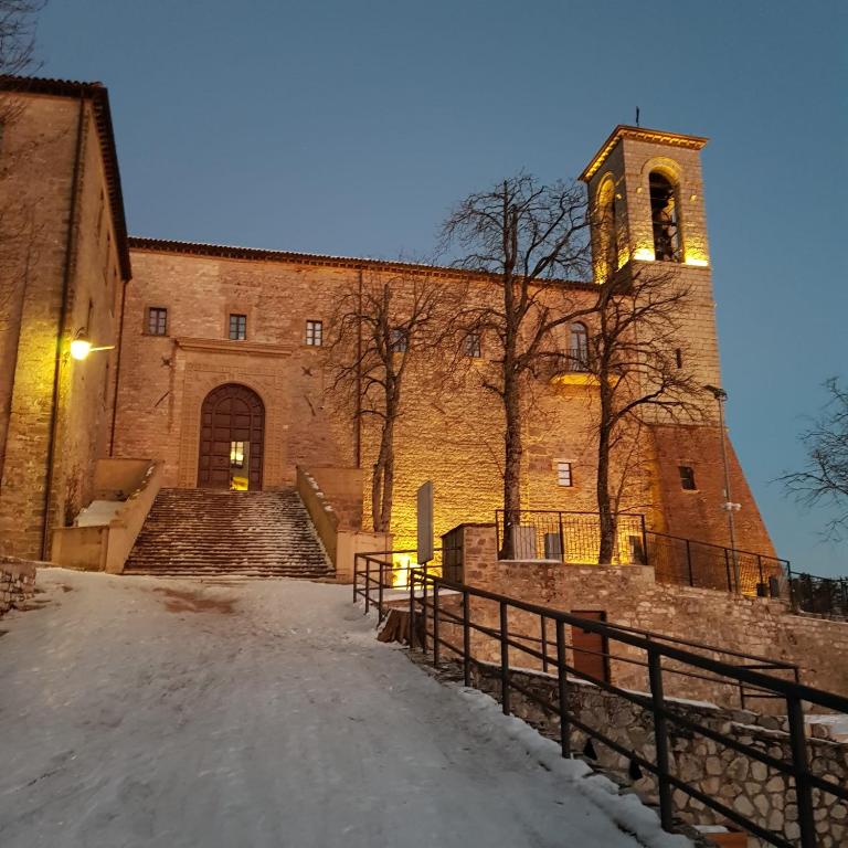 duży ceglany budynek z wieżą zegarową i schodami w obiekcie Appartamento Gattapone 9 w mieście Gubbio