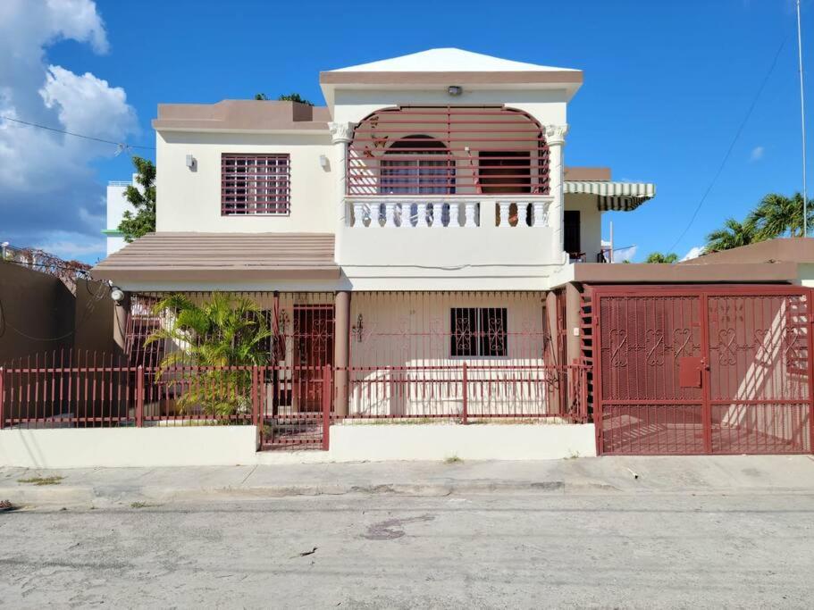 a white house with a red gate and a fence at Dulce hogar del sur, con estacionamiento gratis in Baní