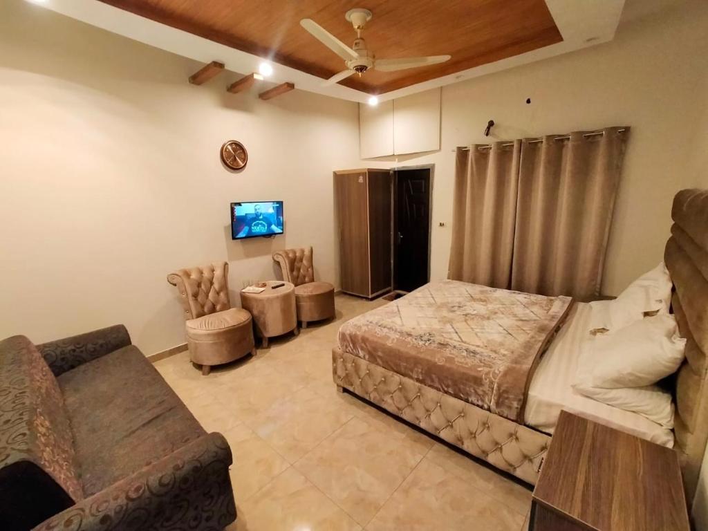 a bedroom with a bed and a couch and a tv at Hotel Day In Emporium in Lahore