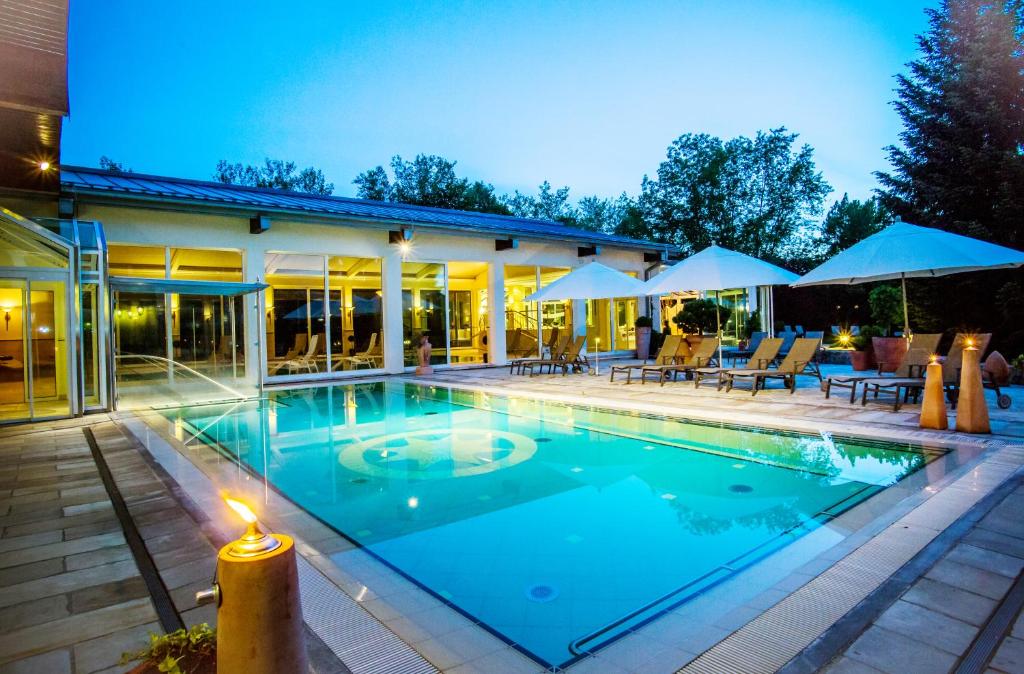 a swimming pool with a candle in front of a house at Thermenhotel Quellenhof in Bad Füssing