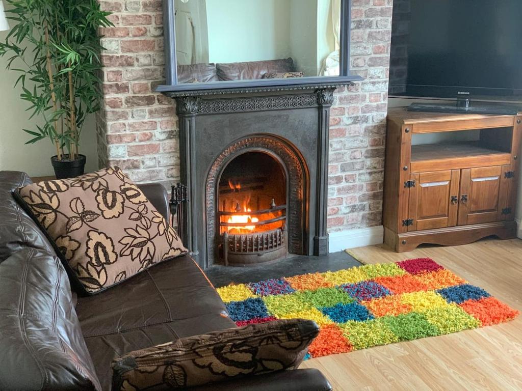 a living room with a fireplace and a couch at Aeronfa in Llanfairfechan