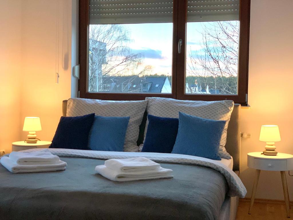 a bedroom with a bed with blue pillows and a window at BALTICUS uroczy apartament w Świnoujściu in Świnoujście