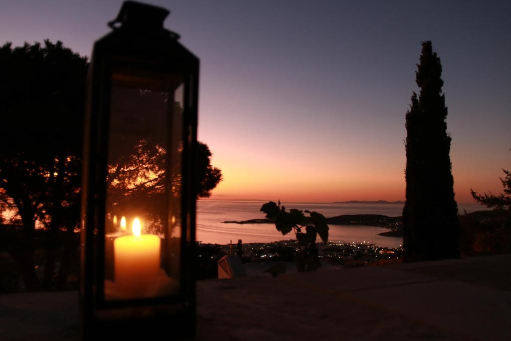 a candle in a lantern with a sunset in the background at Paros Apartments Cottage in Parikia
