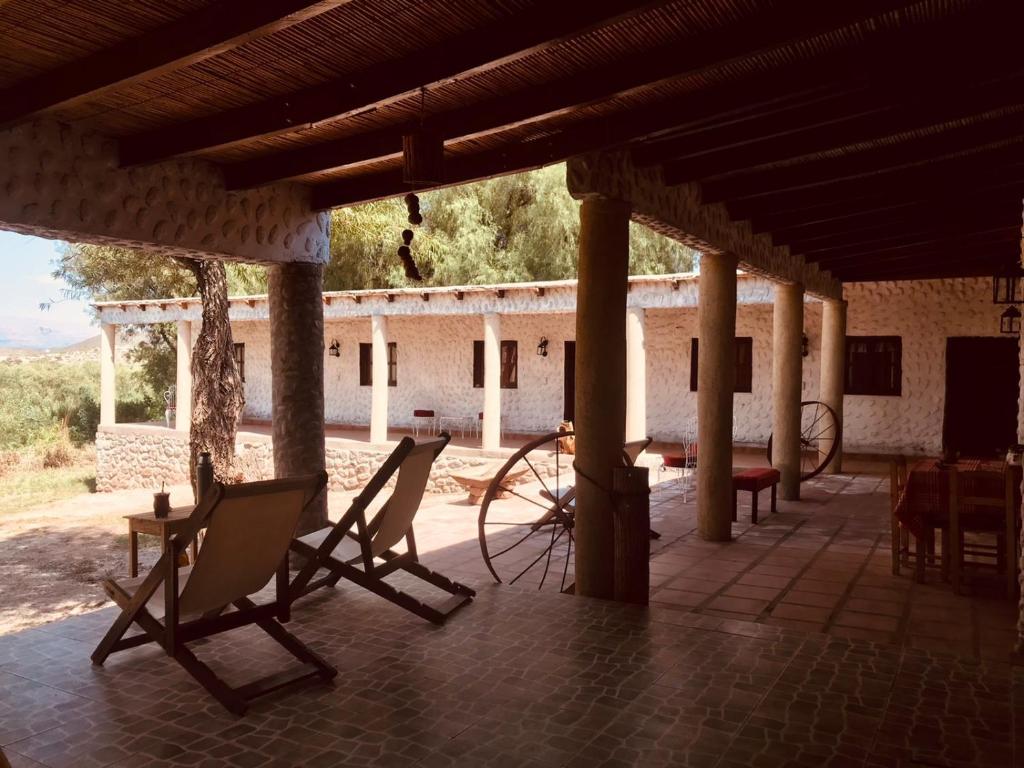 eine Veranda mit Stühlen und Tischen sowie ein Gebäude in der Unterkunft Matices de Molinos Hostal in Molinos