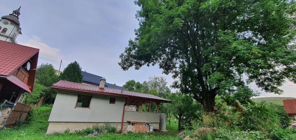 una pequeña casa blanca con un árbol al lado en Chata v záhrade, en Mýto pod Ďumbierom