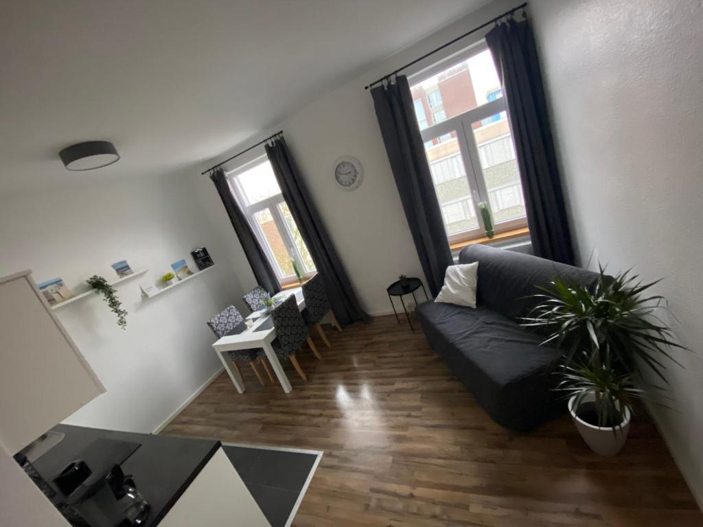 a living room with a black couch and two windows at Ferienwohnung Robbe in Wilhelmshaven