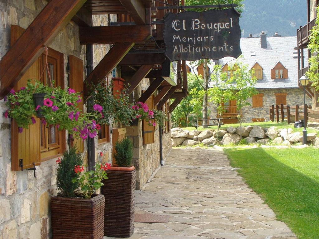 un edificio de piedra con macetas de flores y un cartel en él en El Bouquet, en Pla de l'Ermita