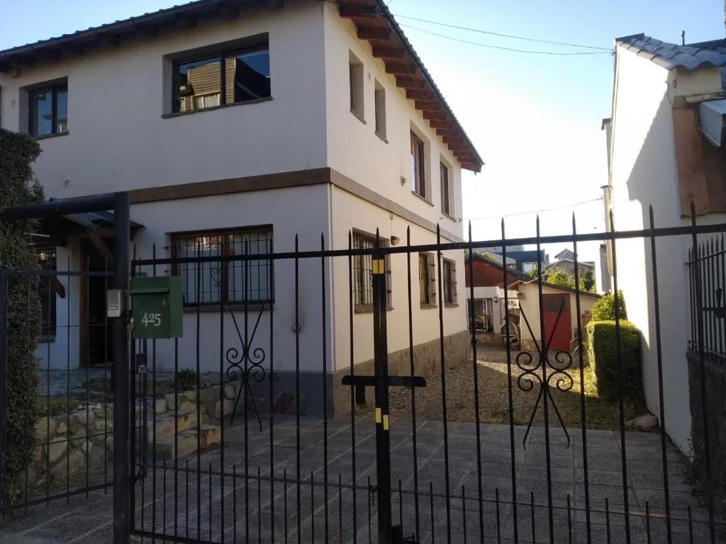 ein weißes Haus mit einem schwarzen Zaun davor in der Unterkunft Casa Centro Bariloche in San Carlos de Bariloche