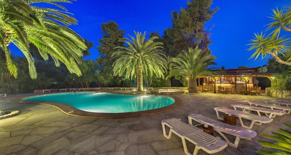 a swimming pool with chaise lounge chairs and palm trees at Hotel Pilalidis in Pefkohori