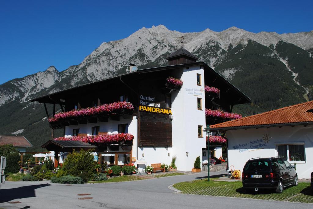 a building with flowers in front of a mountain at Gasthof Panorama in Obsteig